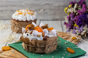 Easter cake (bread) decorated with candies, dried apricots and sunflower seeds on wooden background. Holidays concept