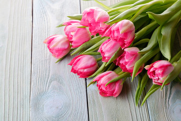 Bouquet of pink fresh tulips on a wooden table, top view