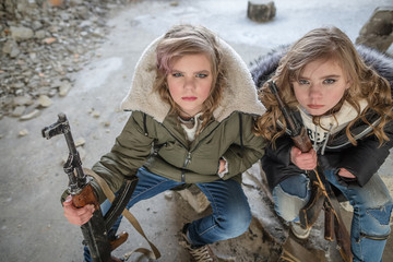 two young girls resting with rifles in a destroyed building in the war