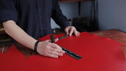 Tanner in the tannery, making measurements and cuts red skin