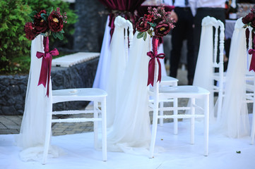 White vintage style chairs decorated with red / claret flowers