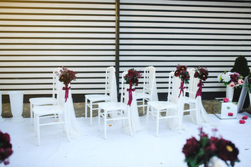White vintage style chairs decorated with red / claret flowers