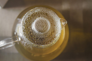 glass teapot with tea with water drops on the lid