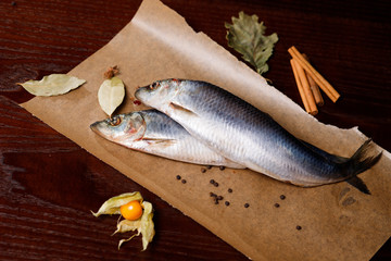 Salted herring fish on paper, on old wooden background .