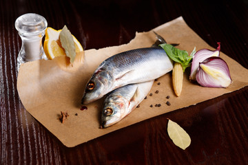Delicious salted herring with red onion, salt and pepper on the old wooden background.
