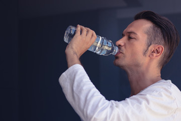 Man drinking water from plastic bottle.