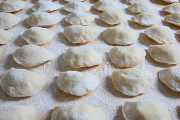 Fototapeta na wymiar Dumplings homemade cheese and potatoes on a pastry board 