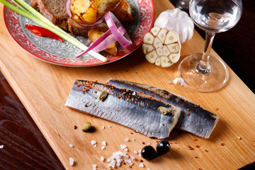 Marinated herring fillet with sliced onions,potatoes, garlic and a glass of vodka.