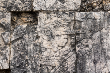 Mayan ball player sculpted on bas relief on the court wall. Detail on Chichen Itza stadium carved on stone. Players had feathered helmets and leather padding for protection. The winner was beheaded. 