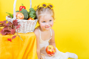 Fototapeta na wymiar Beautiful little happy girl with basket of vegetables and fruits