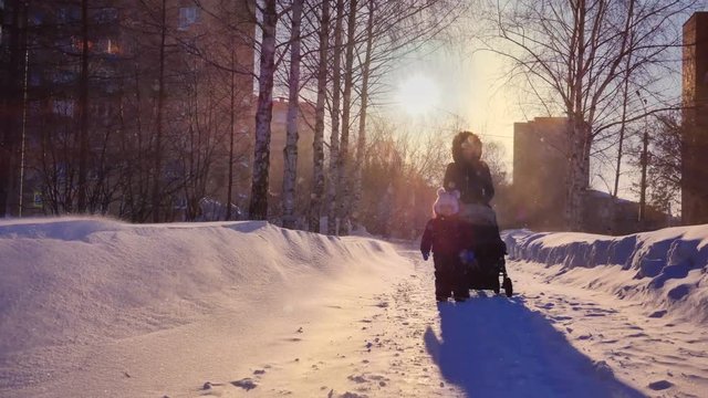 A snowstorm on a sunny day. Mom and daughter are walking in the park. Northern latitudes