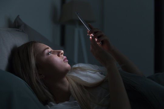 Young Sleepy Exhausted Woman Lying In Bed Using Mobile Phone, Can Not Sleep. Insomnia, Nomophobia, Sleep Disorder Concept