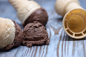 ice cream in waffle cone with utensil on wooden background