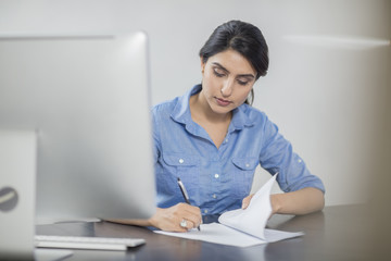 Businesswoman taking notes at desk in office