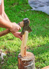 Cutting wood for kindling. Men's hands, axe and firewood