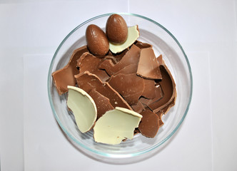 Easter Eggs chocolate. Cracked Eggs chocolate of glass container, white background. Milk and White chocolate