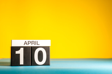 April 10th. Day 10 of april month, calendar on table with yellow background. Spring time, empty space for text