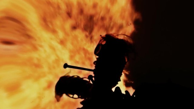 Lens distorted scene: the scay silhouette of a cursed voodoo doll, pierced by big rusty nails, over a fiery fire.
