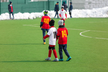 Young kids  football tournament - children play match on the winter soccer field