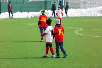 Fototapeta na wymiar Young kids football tournament - children play match on the winter soccer field
