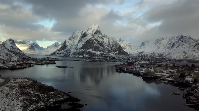 Beautiful super wide-angle winter snowy view of fishing village A, Norway, Lofoten Islands, with skyline, mountains, famous fishing village with red fishing cabins, shot from drone
