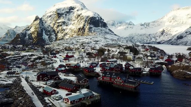 Beautiful super wide-angle winter snowy view of fishing village A, Norway, Lofoten Islands, with skyline, mountains, famous fishing village with red fishing cabins, shot from drone
