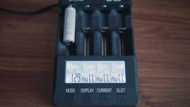 Batteries are charged in a charger. Close up of installing a battery into a charger.