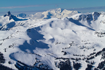 A winter wonderland landscape view of Whistler Mountain with great skiing terrain.  Black Tush can also be seen and the tantalus range in the background - obrazy, fototapety, plakaty