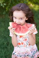 Bright green grass. Little beautiful girl. Juicy, delicious, red watermelon