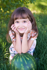Large striped watermelon. Little sweet girl. Summer landscape. Juicy green grass