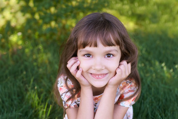 Little sweet, beautiful girl. Brightly green trees. Warm summer time
