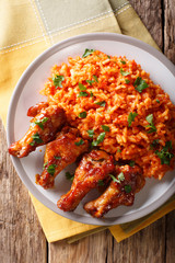 Porcion of African Jollof rice with fried chicken wings close-up on a plate. Vertical top view