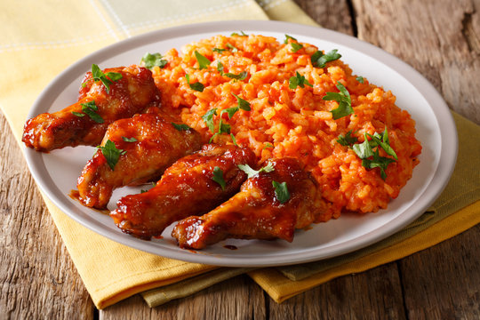 Porcion of African Jollof rice with fried chicken wings close-up on a plate. horizontal