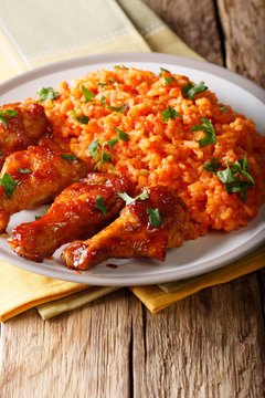 West African food: Jollof rice with fried chicken wings close-up. vertical
