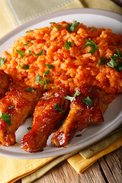 Classic Nigerian Jollof Rice with fried chicken wings close-up. Vertical