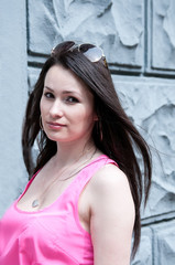 Fototapeta premium Brunette girl in a pink top in summer on the street