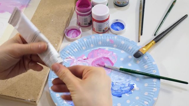 Adult women paint with colored acrylic paints in an art school close up