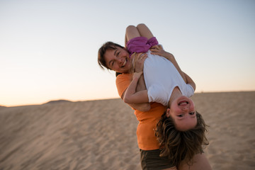 Laughing mother holding her daughter upside down