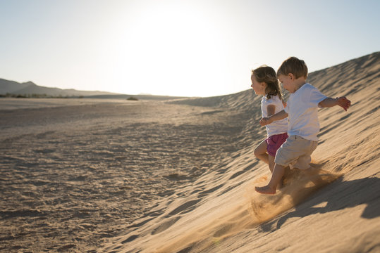Children having fun running down the sand dune