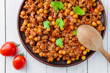 Chile with pork and chickpeas on a plate on a white wooden table