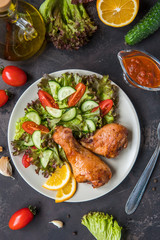 Fried chicken legs and fresh salad on a dark background