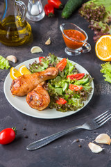 Fried chicken legs and fresh salad on a dark background