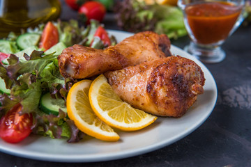 Fried chicken legs and fresh salad on a dark background