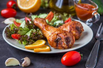 Fried chicken legs and fresh salad on a dark background