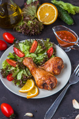 Fried chicken legs and fresh salad on a dark background