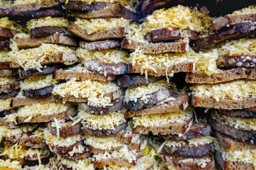 Many bread slices with grated yellow cheese