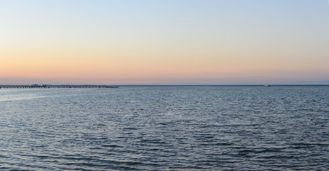 Sea shore yacht on the horizon and pier in the evening panorama
