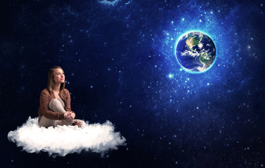 Obraz na płótnie Canvas Woman sitting on cloud looking at planet earth