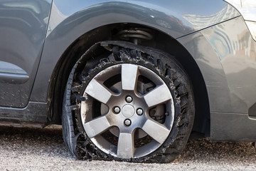 Destroyed blown out tire with exploded, shredded and damaged rubber on a modern suv automobile....