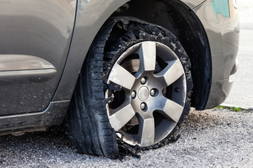 Destroyed blown out tire with exploded, shredded and damaged rubber on a modern suv automobile. Flat low profile tyre on an alloy rim, ripped open in pieces with visible interior. - obrazy, fototapety, plakaty